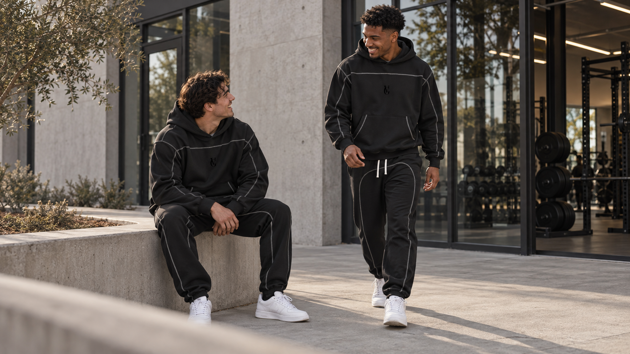 Zwei Männer in Golden Vein Structure Outfits vor einem Gym.