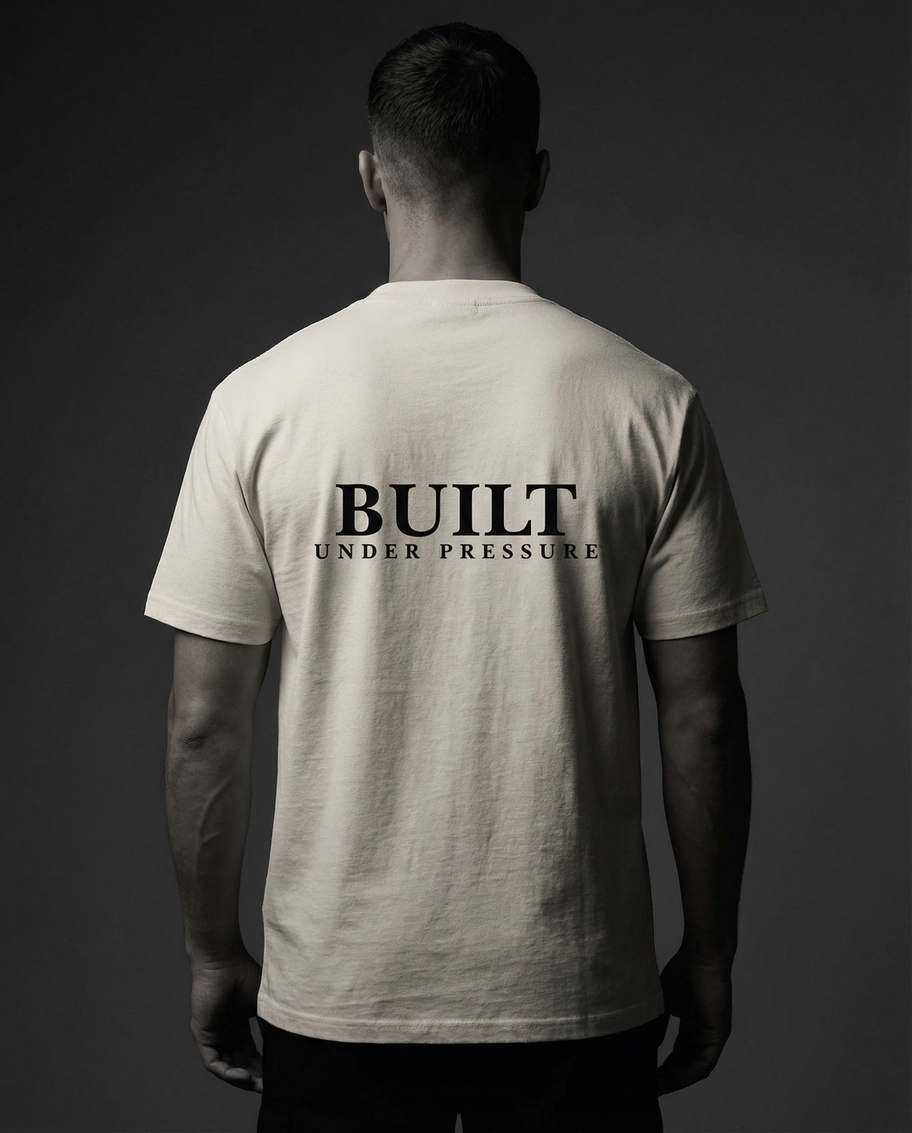 Mann von hinten trägt helles T-Shirt mit Aufdruck „Built Under Pressure“