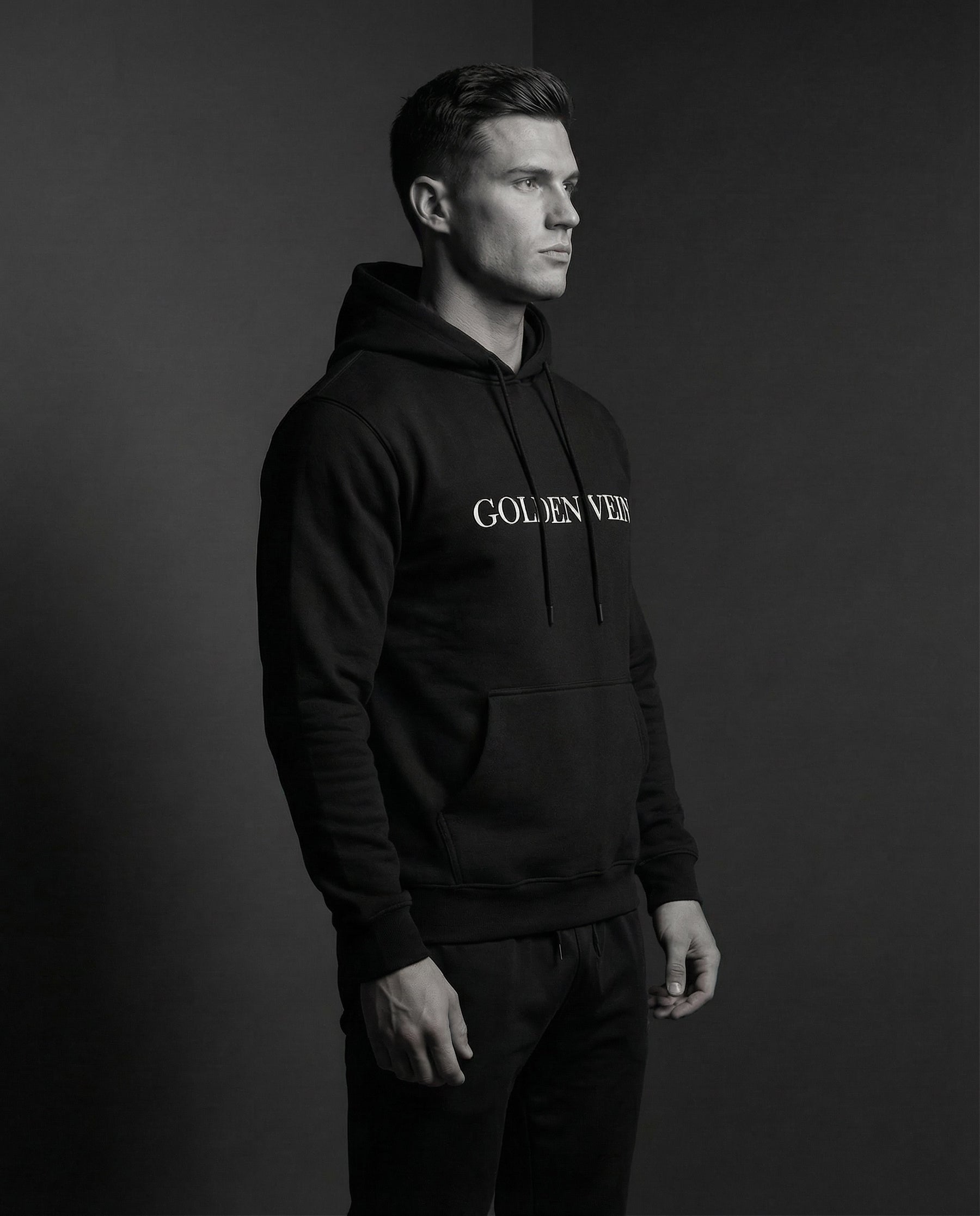 Mann im Profil trägt schwarzen Golden Vein Hoodie im Studio