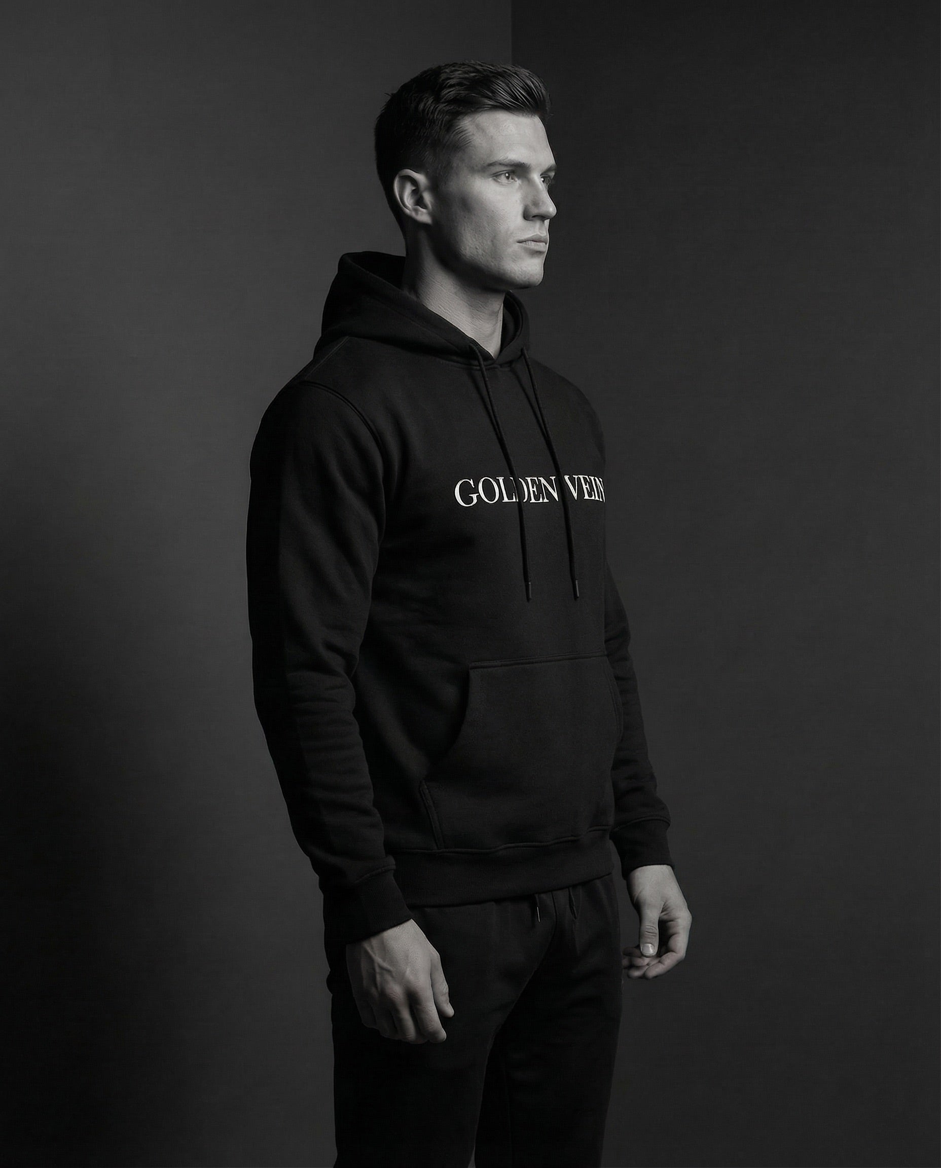 Mann im Profil trägt schwarzen Golden Vein Hoodie im Studio