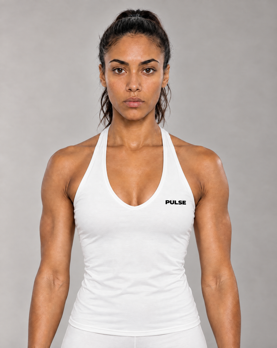 Model trägt PULSE Spectre Halter Tank in Weiß mit schwarzem Brustlogo – Vorderansicht im grauen Studio.