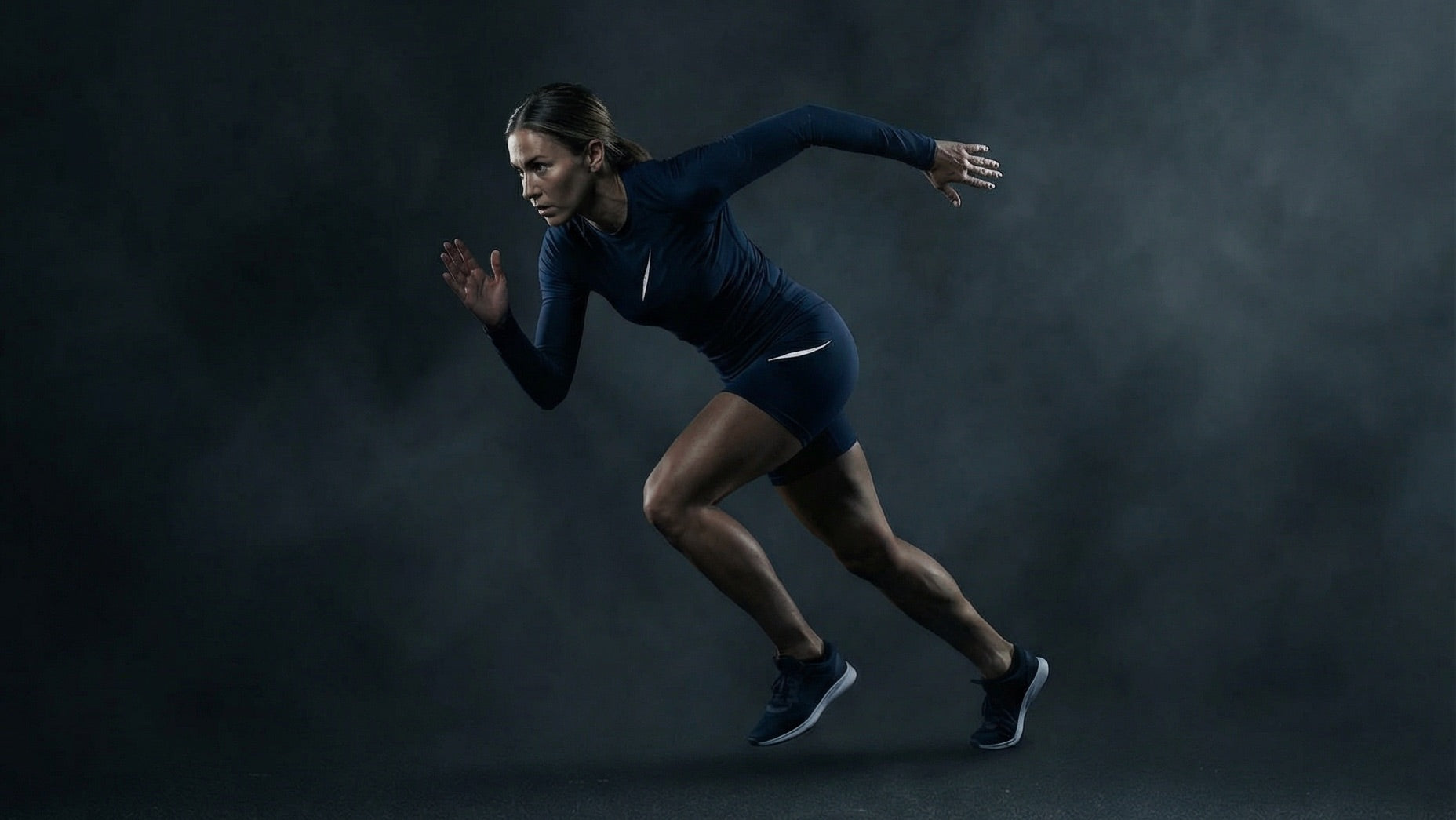 Athletin sprintet in dunkelblauem Performance-Set in Studio-Umgebung